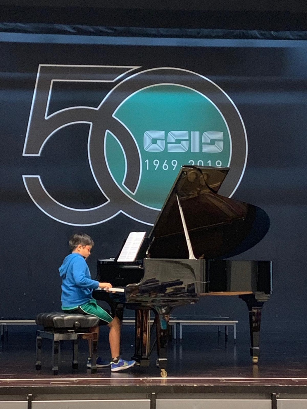 A younger Ashwin playing a grand piano in concert